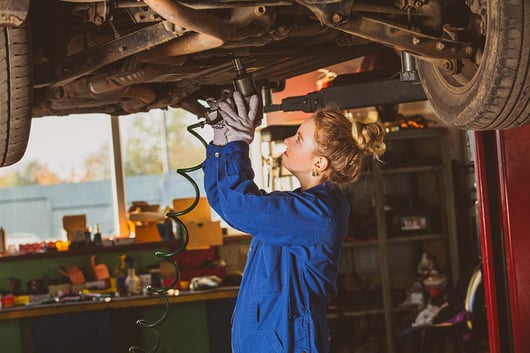 Mécanicienne réparant une voiture dans un garage