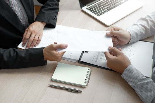 man handing paper to his employee