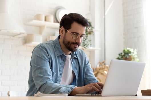 Jeune homme travaillant sur son ordinateur portable à la maison