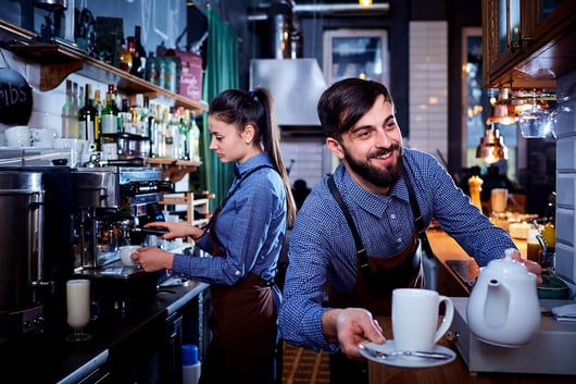 Un serveur et une serveuse préparant des boissons derrière le comptoir d'un bar