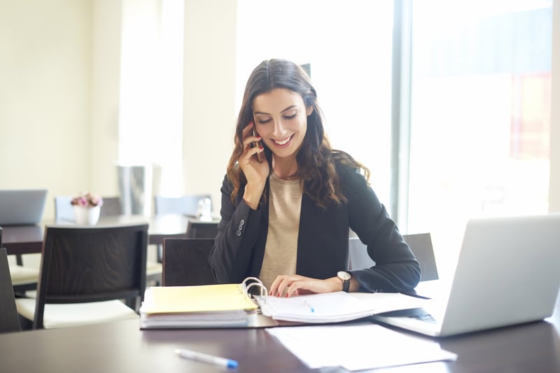 Femme au bureau au téléphone qui sourit